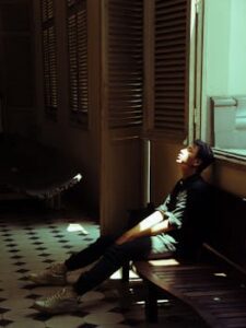 Man in Black Top Sitting on Bench Beside of Door