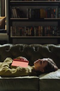 Woman in Black Framed Eyeglasses Lying on Black Leather Couch